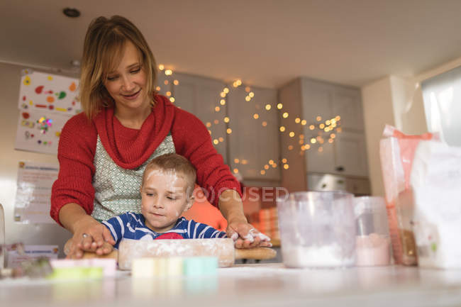 Mutter und Sohn rollen Teig für Plätzchen in der Küche — Stockfoto
