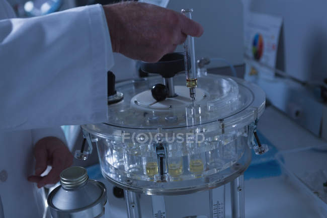 Solución de vertido científico masculino en viales médicos en laboratorio - foto de stock