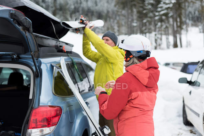 Couple aîné gardant planche à ski sur le toit de la voiture pendant l'hiver — Photo de stock