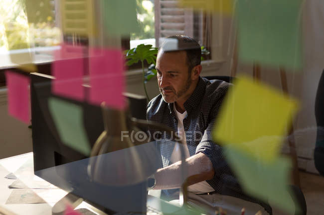 Exécutif masculin attentif travaillant sur l'ordinateur dans le bureau — Photo de stock