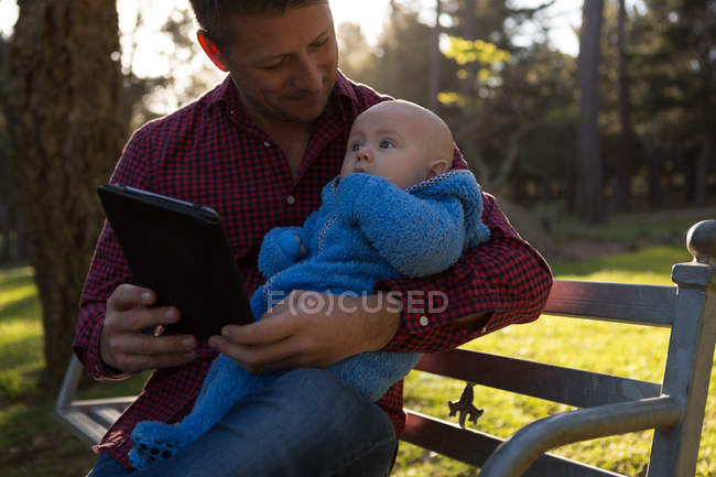 Pai e menino usando tablet digital no parque em um dia ensolarado — Fotografia de Stock