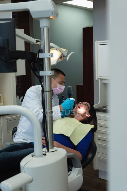 Dentista masculino examinando uma paciente senhora na clínica — Fotografia de Stock