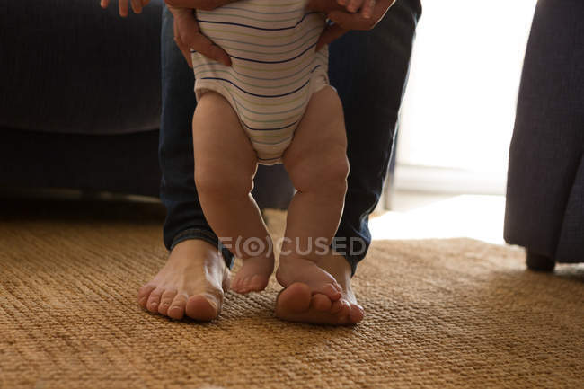 Low section of father helping his baby boy to walk at home — Stock Photo