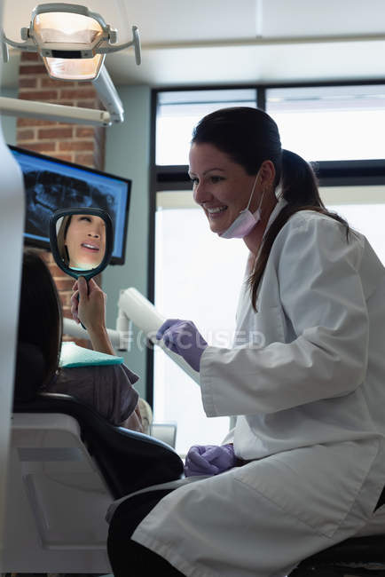 Odontóloga interactuando con paciente en clínica - foto de stock