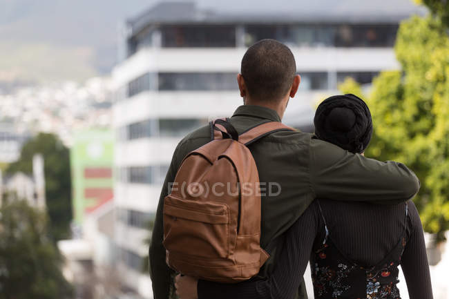 Rear view of couple standing with arm around in city — Stock Photo