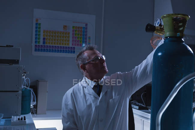 Cientista masculino ajustando medidor de pressão do cilindro em laboratório — Fotografia de Stock