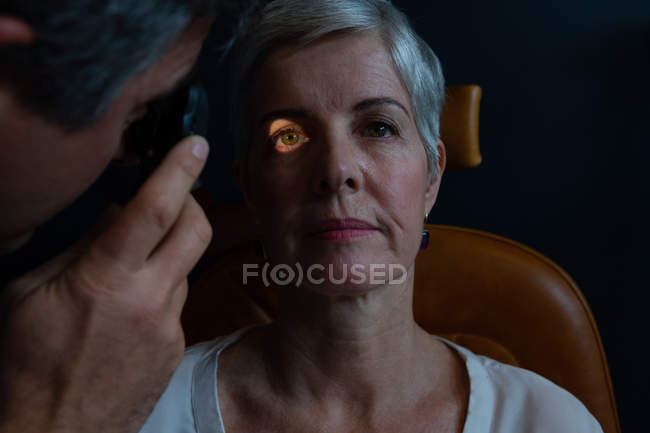 Optometrista examinando os olhos do paciente com oftalmoscópio na clínica — Fotografia de Stock