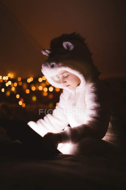 Fille en veste à capuche en utilisant une tablette numérique contre les lumières de Noël — Photo de stock