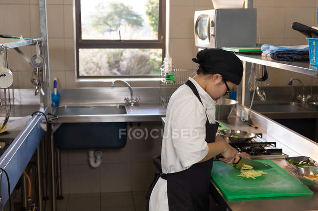 Female chef cutting vegetables in kitchen at restaurant — Stock Photo