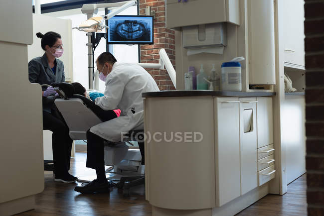 Dentista masculino examinando um paciente com ferramentas na clínica — Fotografia de Stock