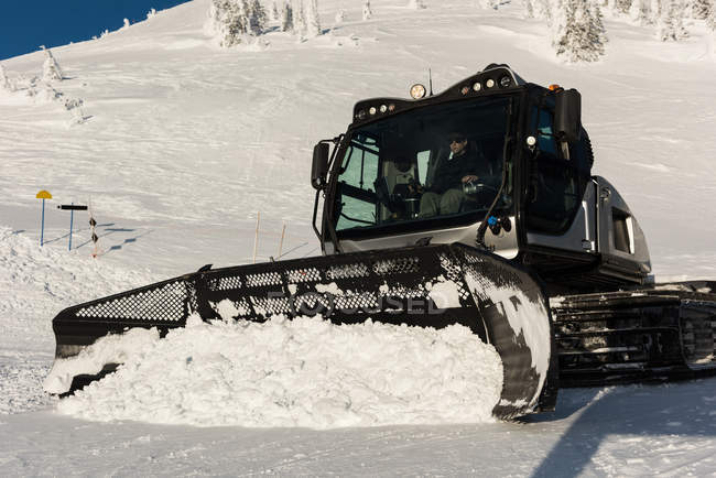 Homem usando caminhão de limpa neve para limpar neve durante o inverno — Fotografia de Stock