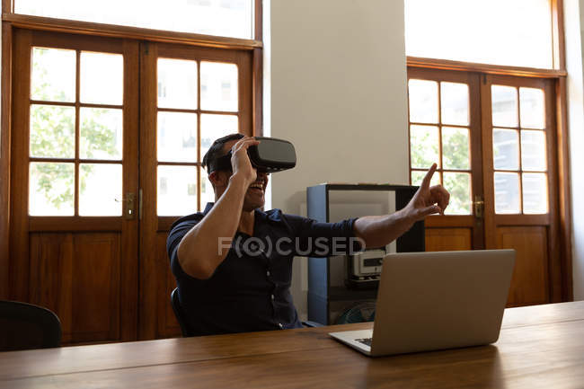Felice dirigente maschile utilizzando cuffia realtà virtuale in ufficio — Foto stock