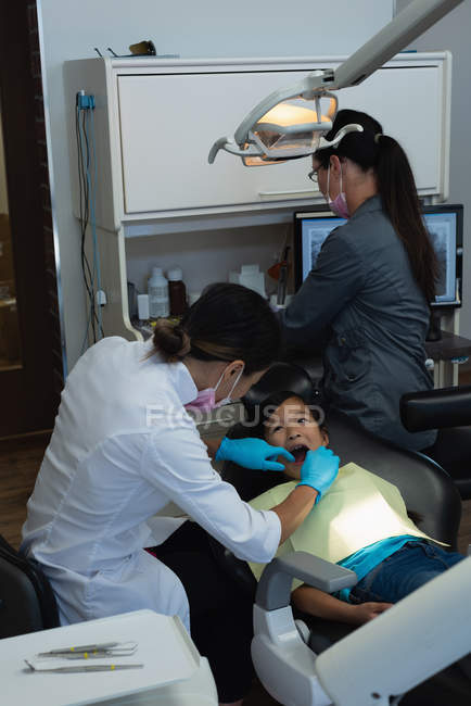Dentista femminile esaminando una ragazza paziente in clinica — Foto stock
