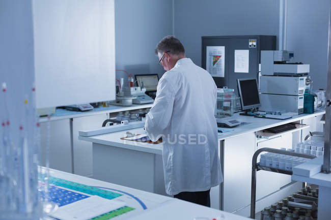 Vista trasera del científico masculino experimentando en laboratorio - foto de stock