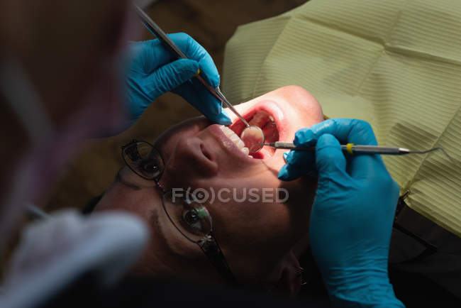 Жіночий стоматолог оглядає пацієнта за допомогою інструментів у стоматологічній клініці — стокове фото