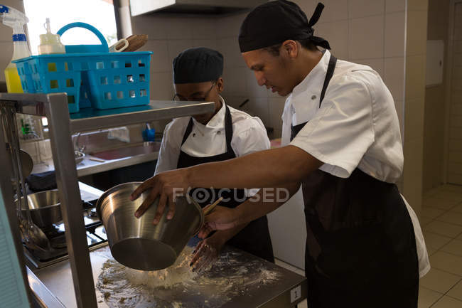 Chef masculino y femenino preparando comida en la cocina del restaurante - foto de stock