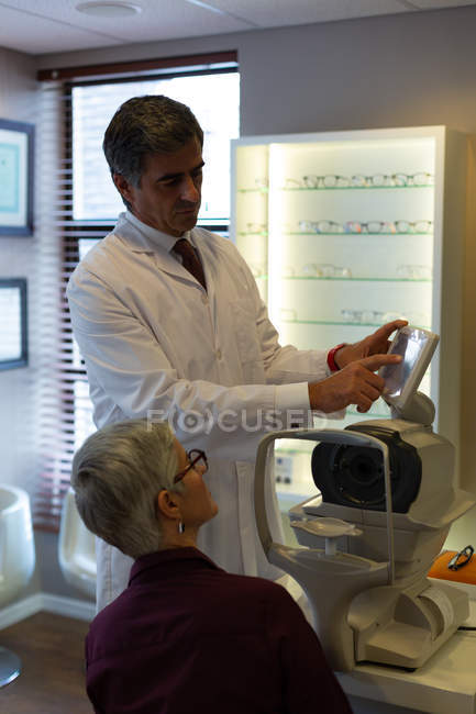 Optometrista che spiega il rapporto visivo sullo schermo dei rifrattori automatici in clinica — Foto stock