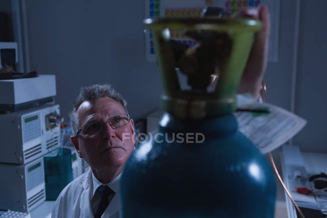 Close-up do cientista masculino ajustando medidor de pressão do cilindro em laboratório — Fotografia de Stock