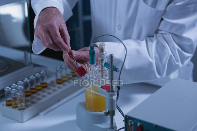 Sección media del científico masculino que experimenta en laboratorio - foto de stock