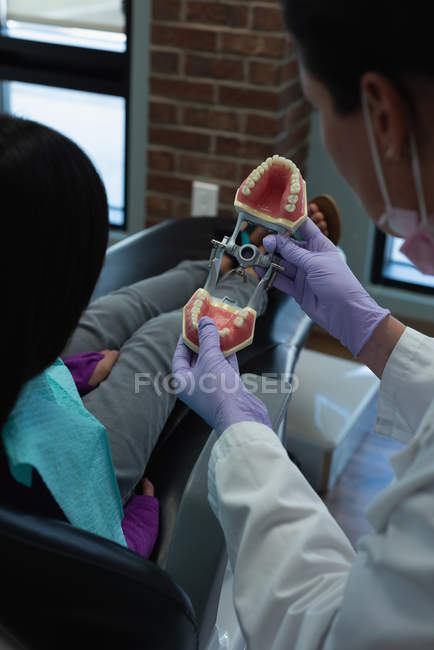 Dentista femminile che spiega sul modello di denti in clinica — Foto stock