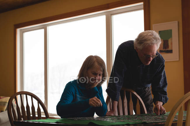 Senior couple playing jigsaw puzzle at home — Stock Photo