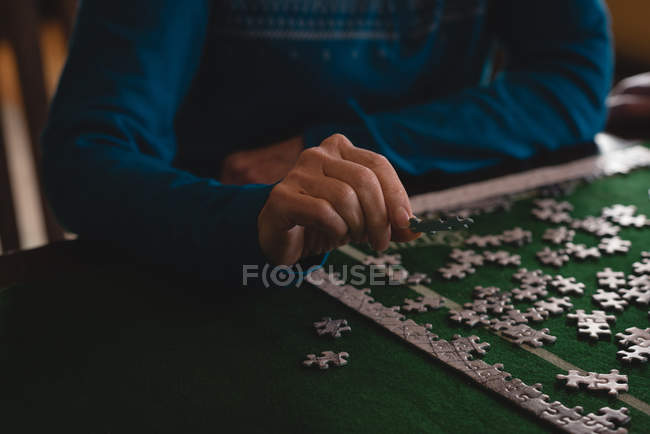 Sección media de la mujer mayor jugando rompecabezas en casa - foto de stock