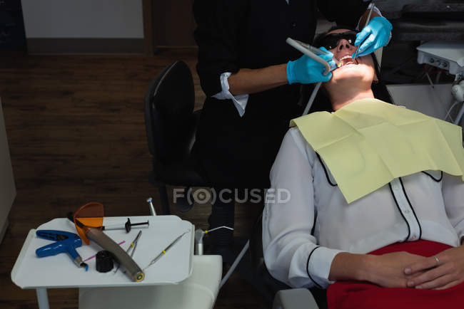 Odontoiatra che esamina una paziente con strumenti in clinica dentale — Foto stock