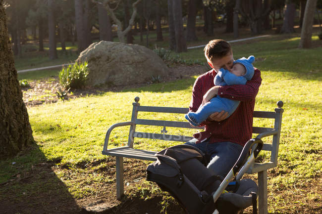 Батько цілує свого хлопчика в парку в сонячний день — стокове фото