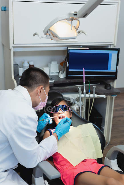 Male dentist examining a patient with tools in clinic — Stock Photo