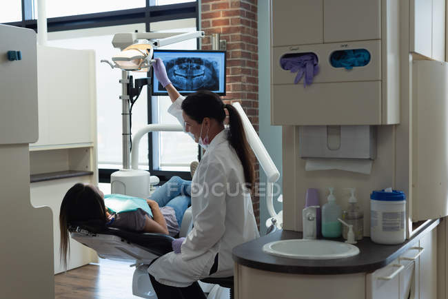Dentista feminina examinando uma paciente na clínica — Fotografia de Stock