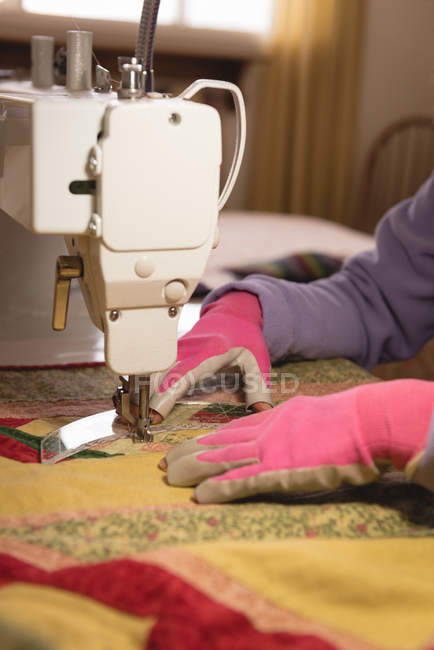 Femme coud des vêtements sur la machine à coudre à la maison — Photo de stock