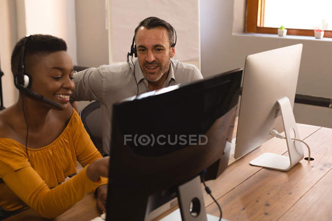 Glückliche Geschäftskollegen diskutieren am Computer im Büro — Stockfoto