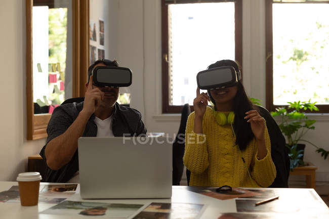 Business colleagues using virtual reality headset on desk in office — Stock Photo