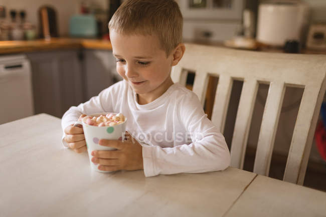 Garçon souriant tenant une tasse de guimauves — Photo de stock