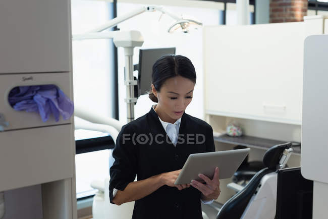 Dentista feminina atenta usando tablet digital na clínica odontológica — Fotografia de Stock