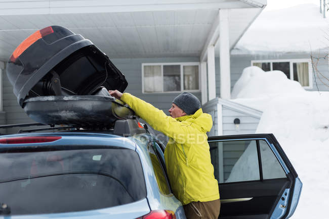 Seitenansicht eines älteren Mannes, der sein Gepäck auf dem Autodach aufbewahrt — Stockfoto