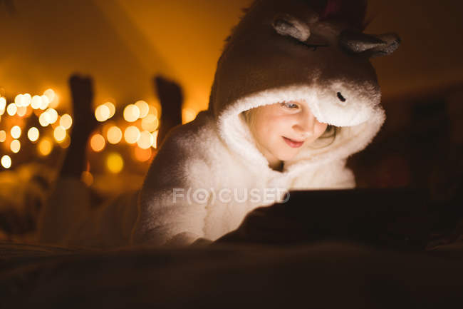 Smiling girl using digital tablet against Christmas lights — Stock Photo