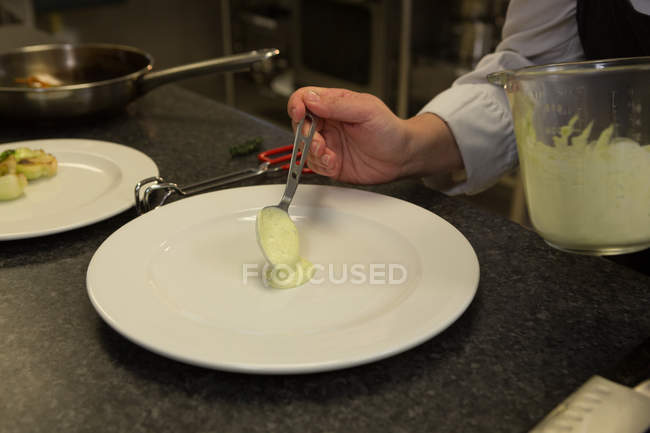 Gros plan du chef servant de la sauce dans une assiette — Photo de stock