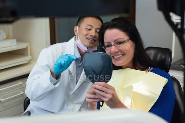 Dentiste masculin interagissant avec le patient en clinique — Photo de stock
