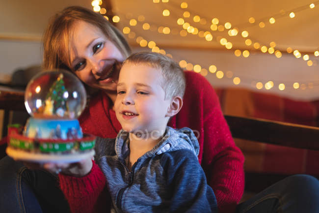 Madre e figlio in possesso di albero di Natale palla di neve a casa — Foto stock