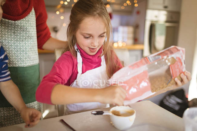 Menina derramando os ingredientes no copo em casa — Fotografia de Stock