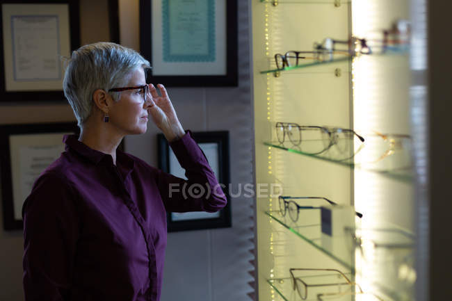 Senior woman selecting frame in clinic — Stock Photo