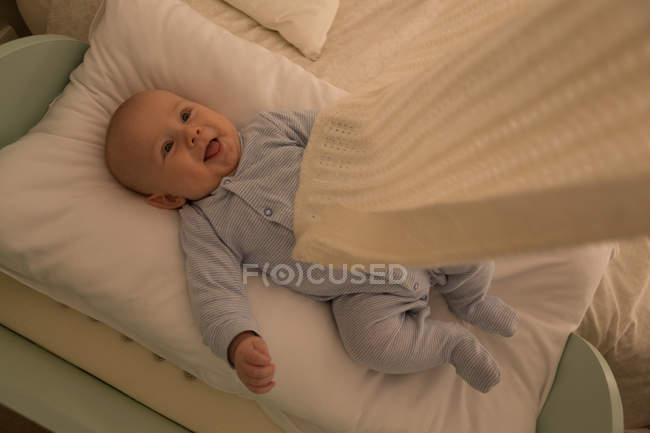 Дитячий хлопчик посміхається, розслабляючись на дитячому ліжку вдома — стокове фото