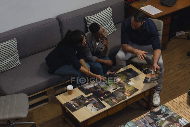 Business colleagues discussing over a photos on desk in office — Stock Photo