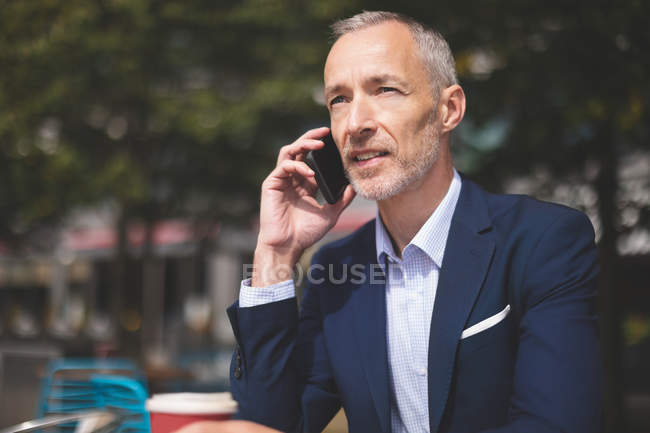 Primer plano del hombre de negocios hablando por teléfono móvil en la cafetería al aire libre - foto de stock