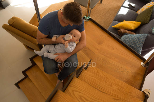 Vater füttert seinen kleinen Jungen auf der Treppe zu Hause mit Milch — Stockfoto
