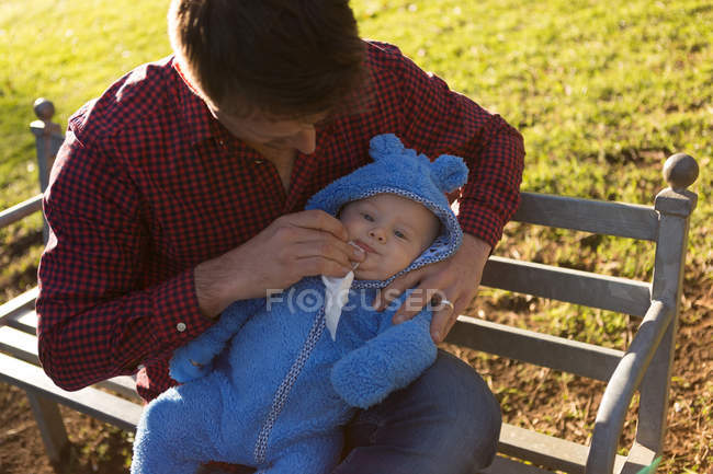 Père tenant son petit garçon dans le parc par une journée ensoleillée — Photo de stock