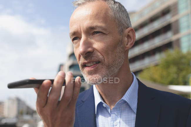 Close-up of businessman talking on mobile phone in city — Stock Photo