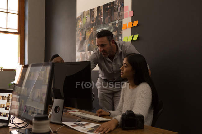 Compañeros de negocios discutiendo sobre una computadora en el escritorio en la oficina - foto de stock