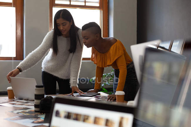 Business colleagues discussing over a laptop on desk in office — Stock Photo